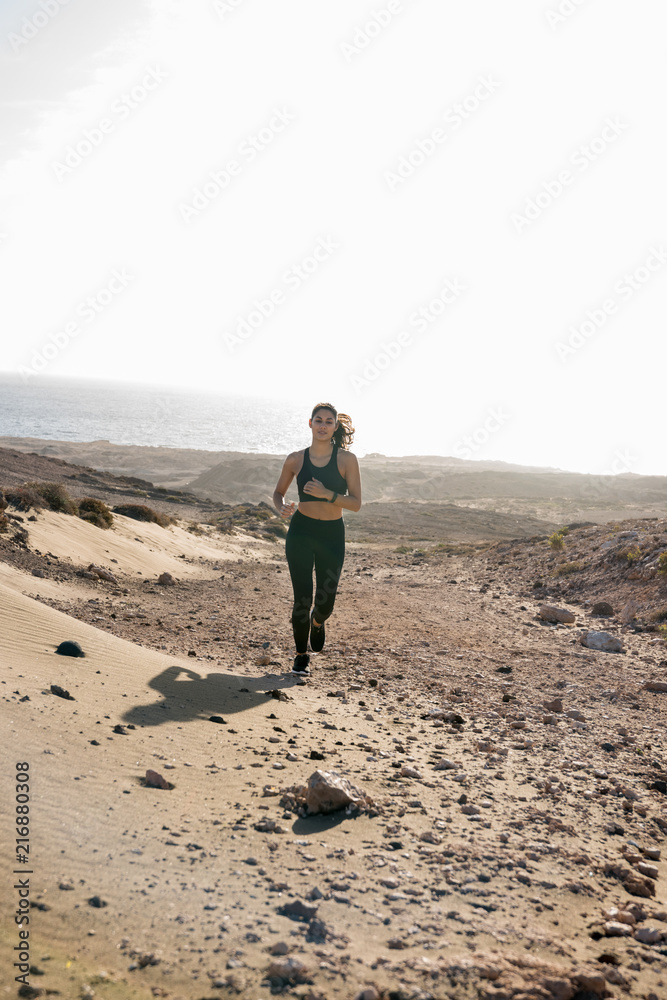 Naklejka premium Woman running across a sand dune in the desert