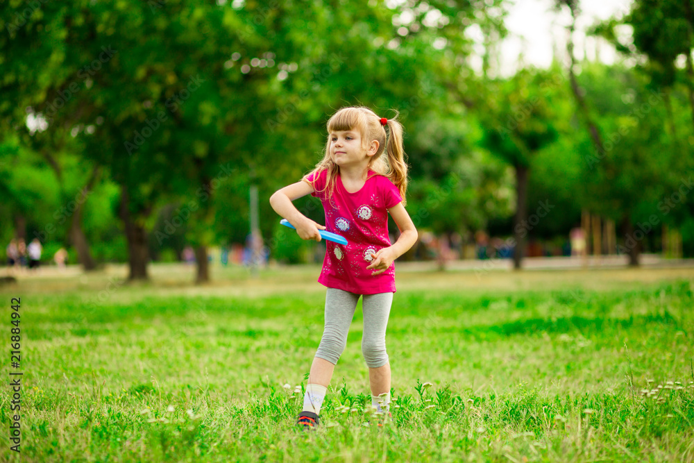 Little girl play with flying disk in motion, playing leisure activity games in summer park