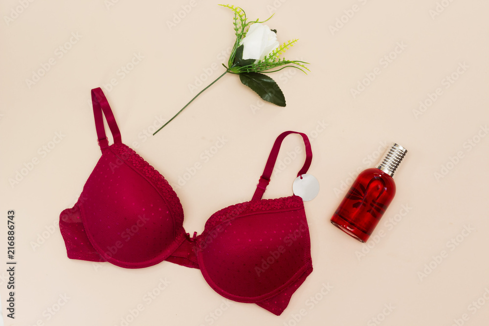 Beautiful female underwear. red bra lying, white flower, perfume bottle on  pink background Stock Photo