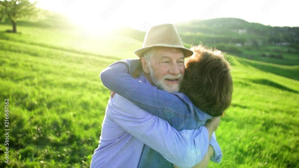 Senior couple kissing and hugging outside in spring nature at sunset. Senior couple kissing and hugging outside in spring nature at sunset.