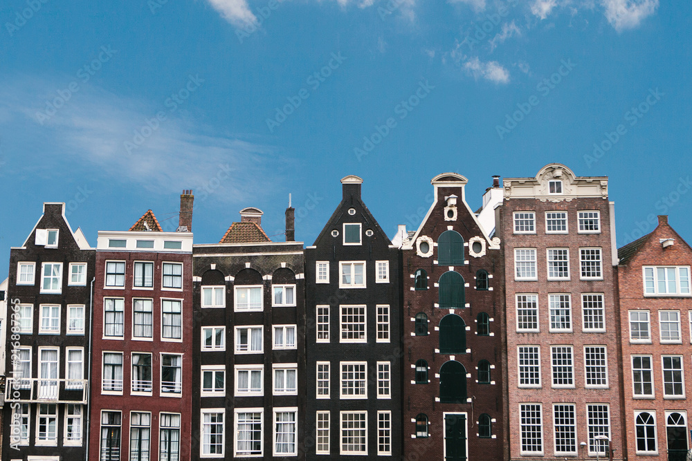 Traditional houses in Amsterdam in the Netherlands in a row against the blue sky.