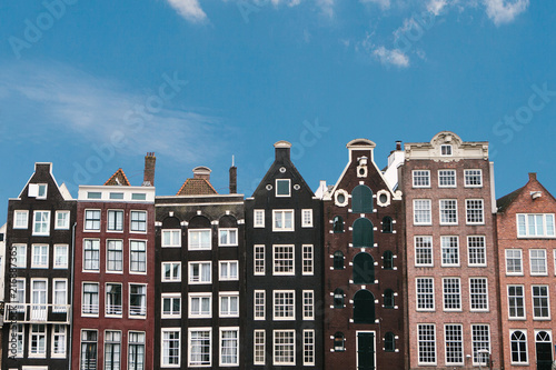 Obraz na płótnie Traditional houses in Amsterdam in the Netherlands in a row against the blue sky. w salonie