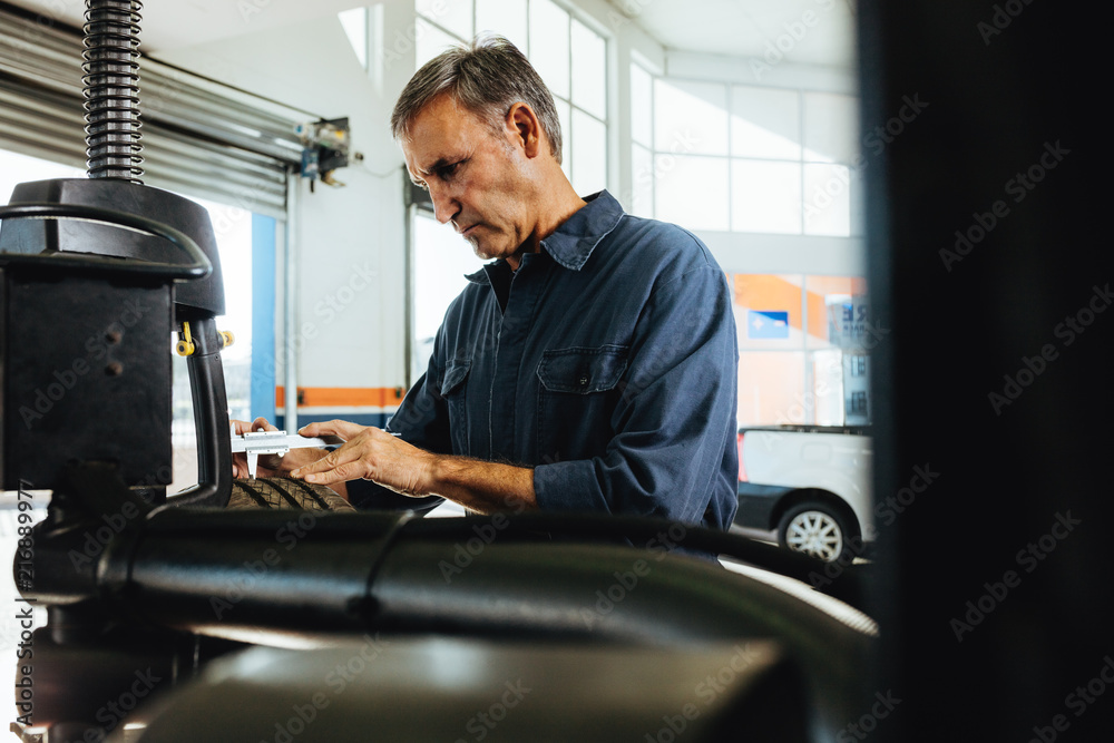 Technician working in automobile tyre mounted on machine Technician working in automobile tyre mounted on machine