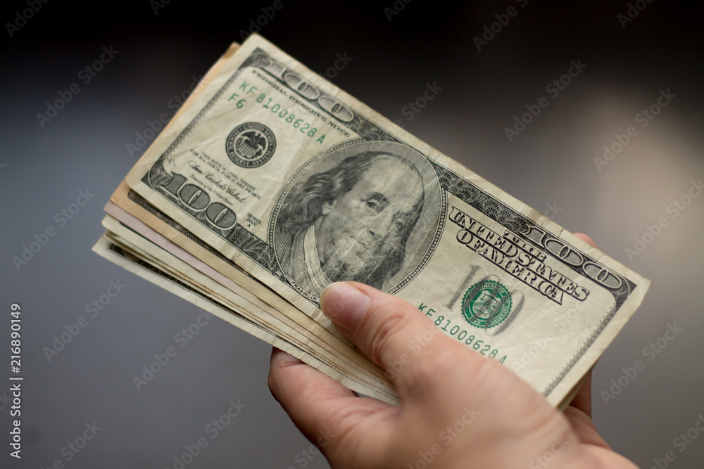  a human hand donates 100 dollars of banknotes, cash for the purchase of goods