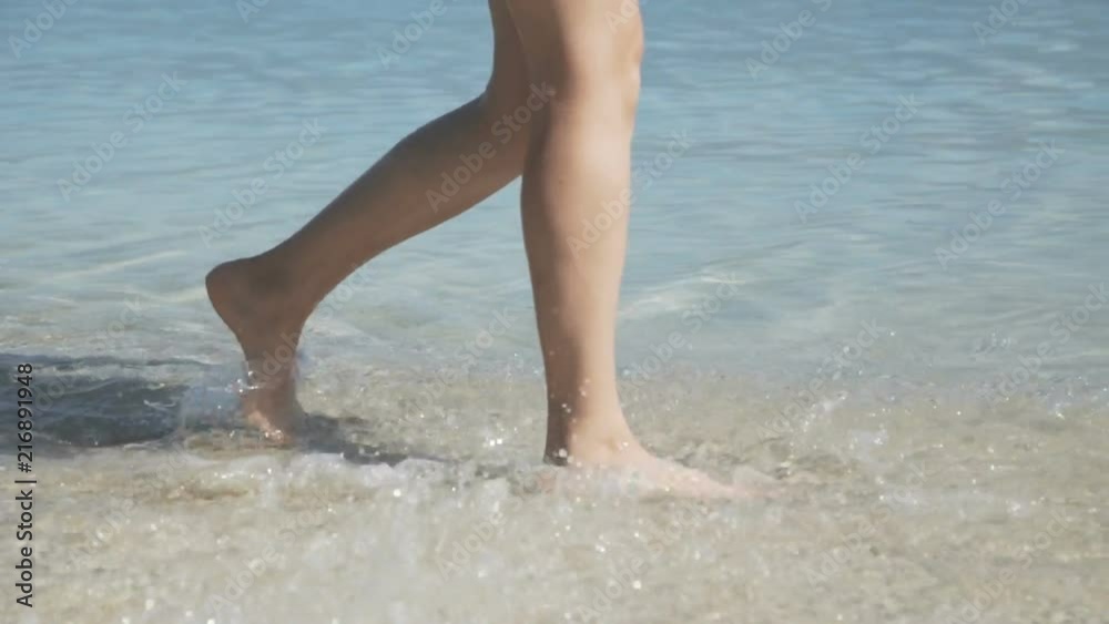 Unrecognizable female bare lags walks in the blue sea Unrecognizable female bare lags walks in the blue sea