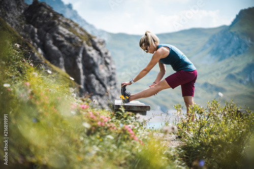 Beautiful Sportive Hiker Girl Stretching while having a break near a beautiful Alpine Lake in the Austrian Alps