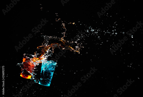 Fototapeta Naklejka Na Ścianę i Meble -  Splash and fire of two glasses on a black backdrop.