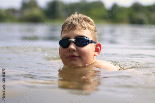 boy in swimming goggles swimming in the lake