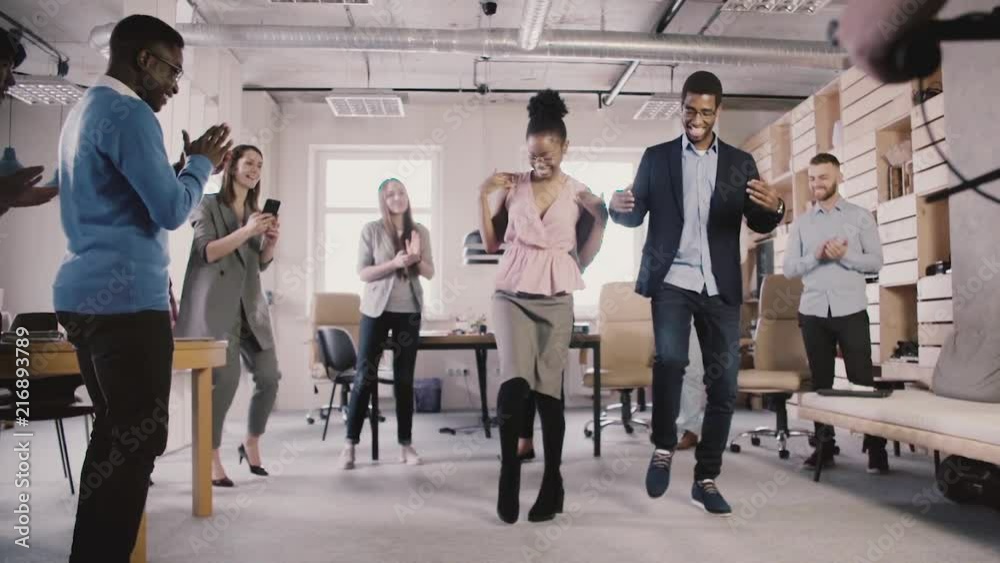 Happy African American employees doing fun ethnic dance at office party, celebrating business achievement slow motion. Happy African American employees doing fun ethnic dance at office party, celebrating business achievement slow motion.