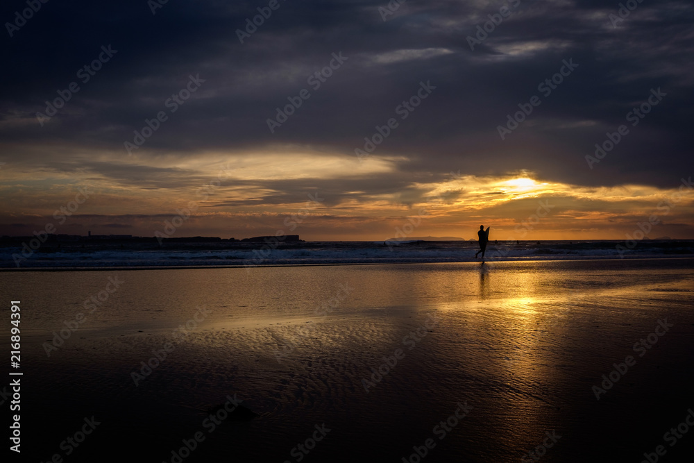 Silhouette of surfer on the beach in late sunset.