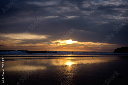 Silhouette of surfers on the beach in late sunset.