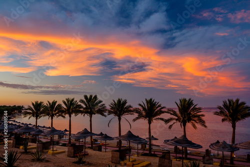 Amazing Sunset on the Beach with Parasols and Palm Trees at Calimera Habiba Beach Resort © SaKaLovo