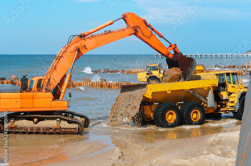 Construction of breakwaters in the sea. Construction equipment and machinery on the seashore.