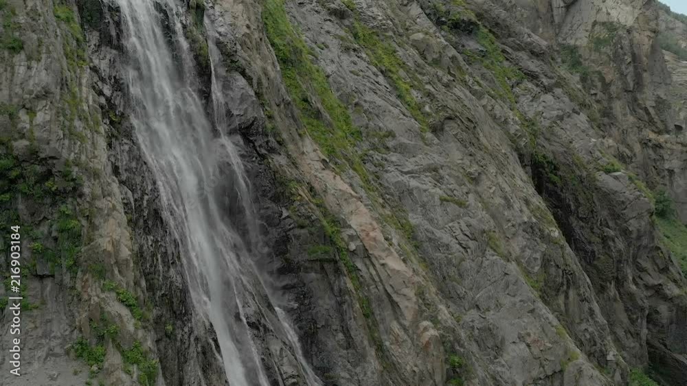 Tracking and top shot Air shot from a stream of water splashing waterfall on a rock wall in the Caucasus Mountains. Around the jet of the waterfall