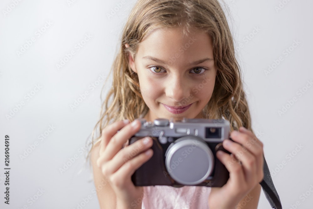 portrait of a young beautiful kid holding a vintage camera and smiling. white background. Kids indoors. Photography concept portrait of a young beautiful kid holding a vintage camera and smiling. white background. Kids indoors. Photography concept