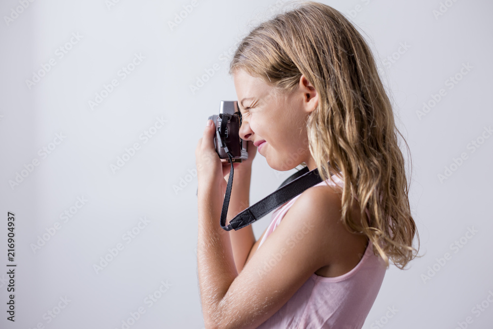 portrait of a young beautiful kid holding a vintage camera and smiling. white background. Kids indoors. Photography concept portrait of a young beautiful kid holding a vintage camera and smiling. white background. Kids indoors. Photography concept
