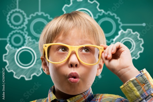 Young boy in glasses on blackboard background