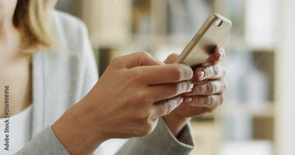Close up of the businesswoman's hands texting and typing on the smartphone at her workplace in the office. Close up of the businesswoman's hands texting and typing on the smartphone at her workplace in the office.