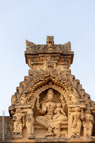 Shravanabelagola, Karnataka, India - November 1, 2013: Brown stone with black mold deity statue in niches on edge of roof at Jain Tirth building. Laksmi with five figurines.