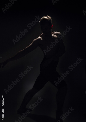 one ballet dancer, dark black background, backlit backlighting.