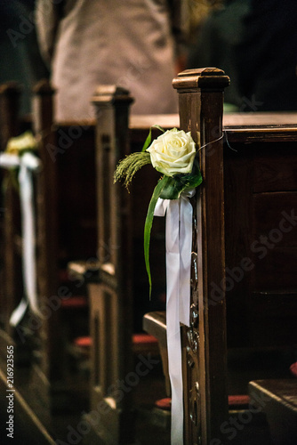 Beautiful flower wedding decoration in a church hang on the seat rows setting in the Chapel, ceremony selective focus photo