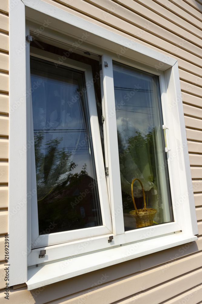 Window of a private house on a background of beige siding. Window of a private house on a background of beige siding.
