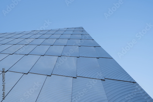 shiny, stainless steel shingles overlap the side of a building
