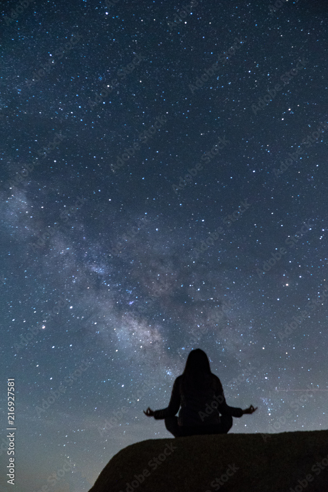 Girl meditating in lotus pose under the beautiful Milky Way night sky Girl meditating in lotus pose under the beautiful Milky Way night sky