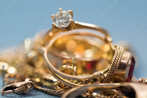  Real gold rings with diamond, chain, close up macro shot on blue background.