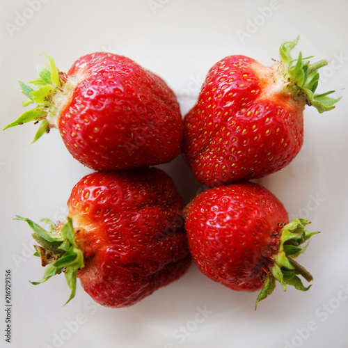 Red strawberries on a white saucer. Natural food, a healthy lifestyle. photo