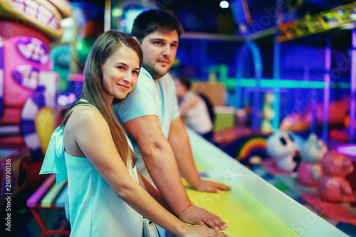 Young attractive couple man and woman are smiling in a children's entertainment center indoors.