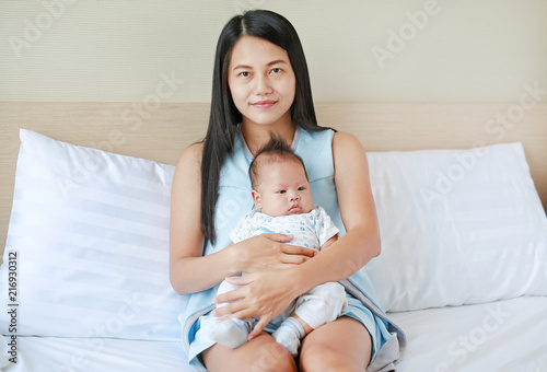 Portrait of mother hugging her baby in the bedroom.