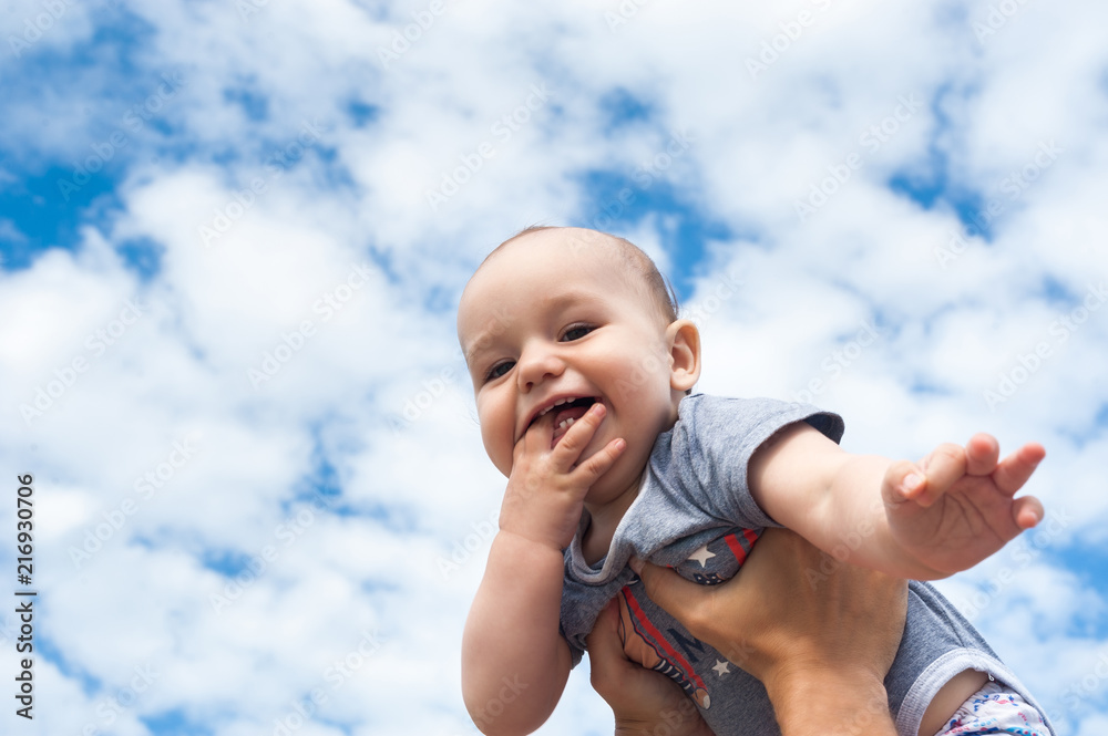 Happy kid on a background of blue sky and clouds - obrazy, fototapety, plakaty 