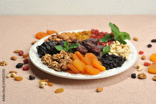 Nuts and dried fruits on a large white dish. On a plate of raisins, dried apricots, prunes, dates, cherries, cashews, almonds, walnuts. Light background. Close-up. 