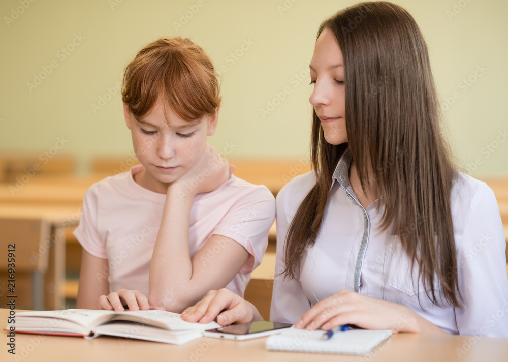 2 student girls are sitting at a Desk 2 student girls are sitting at a Desk