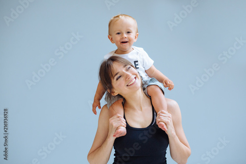 фотографія European sporty mother playing with cute toddler baby boy
