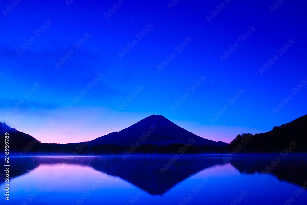 夜明け前の毛嵐が立ち込める精進湖と富士山

