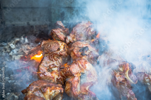 juicy pieces of barbeque shish kebab are prepared on the grill in thick smoke