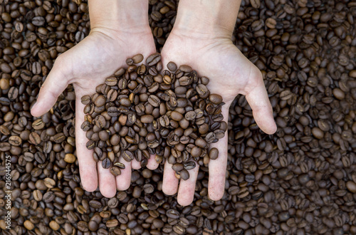 Close-up view of roasted coffee beans in man s hands.