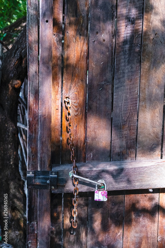 bright colored padlock on a wooden door near the chain