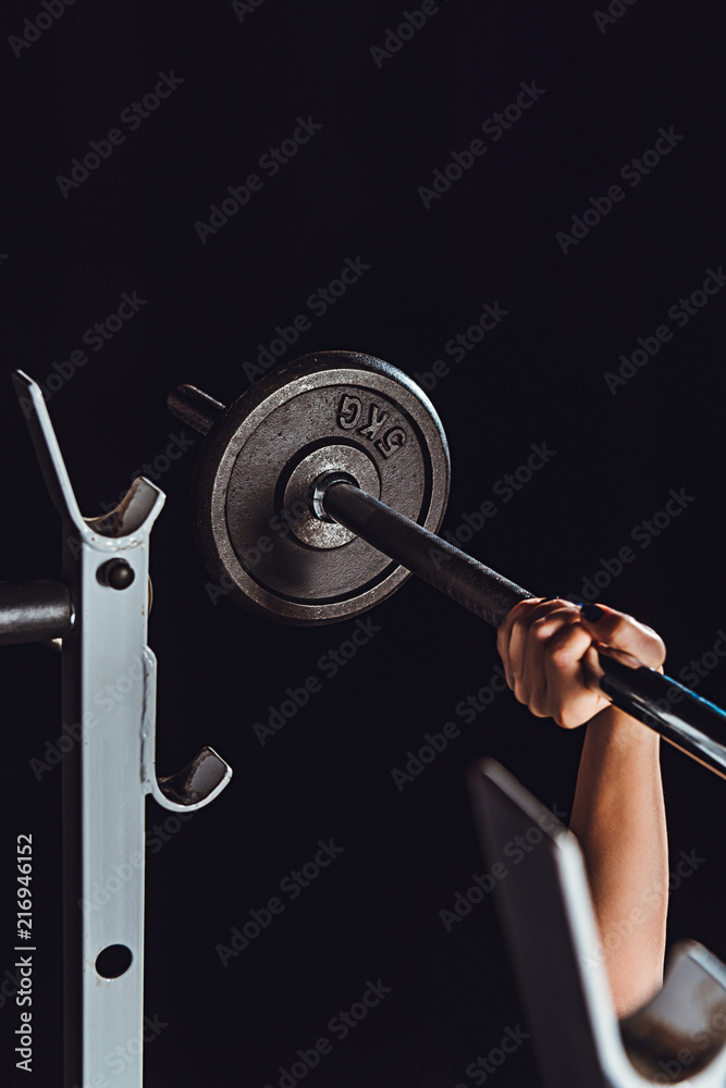 cropped image of female bodybuilder doing exercise with barbell at gym, black background cropped image of female bodybuilder doing exercise with barbell at gym, black background