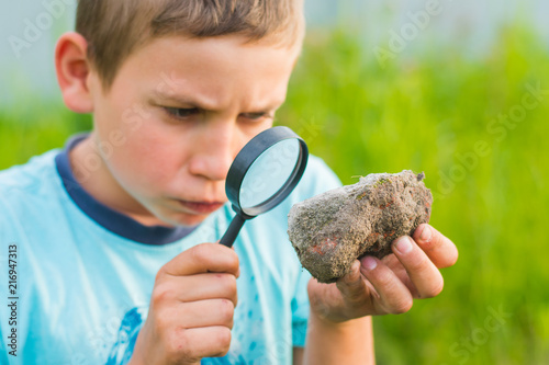 schoolboy looking through a magnifying glass in nature