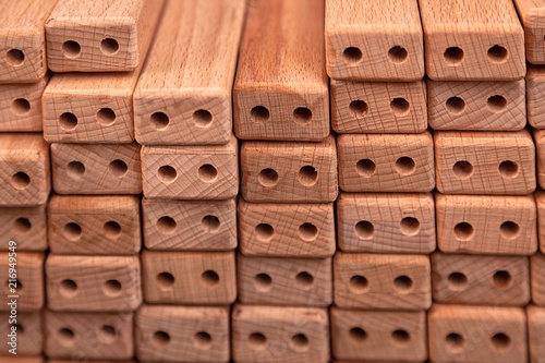 A close-up of the same wooden bars with drilled holes for the manufacture of furniture lie in rows