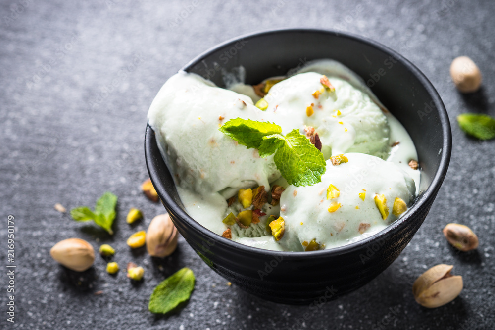 Pistachios ice cream in bowl on black stone table. Pistachios ice cream in bowl on black stone table.