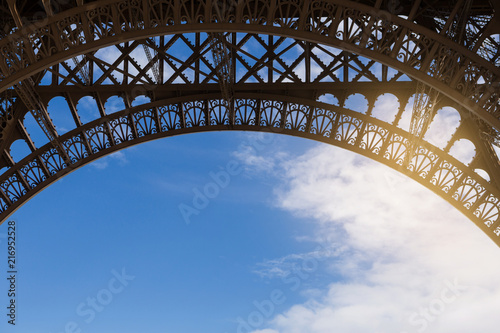 arch of the eiffel tower close-up against the blue sky, concept of romance and traveling together © aneduard