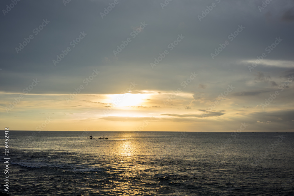 Ocean Sunset in Bali, Indonesia with small boats on water
