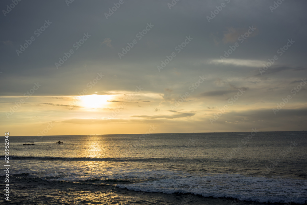 Ocean Sunset in Bali, Indonesia with small boats on water