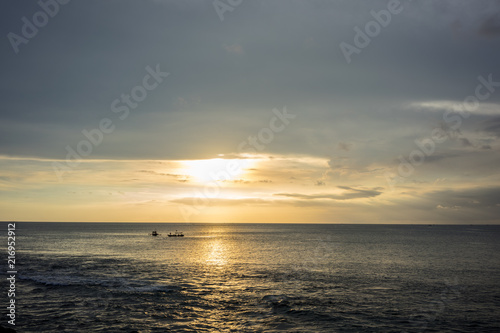 Ocean Sunset in Bali, Indonesia with small boats on water