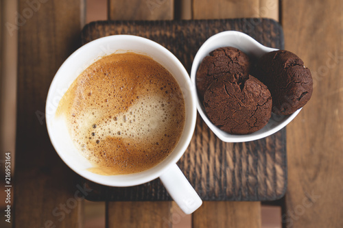 Chocolate cookies with dark chocolate and cup of coffee on a wooden background. photo