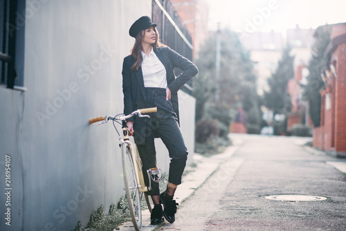 Woman standing on the street next to her fixie bicycle.